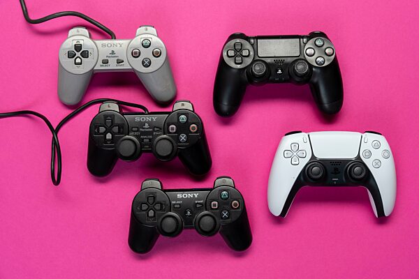 Verschiedene Generationen Gamecontroller der Playstation Spielekonsole, von Model 1-5 vor einfarbig pinken Hintergrund, top view
