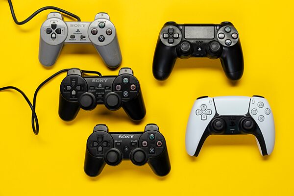 Verschiedene Generationen Gamecontroller der Playstation Spielekonsole, von Model 1-5 vor einfarbig gelben Hintergrund, top view