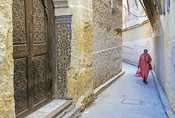 Schöne geschnitzte Holztür und muslimische Frau mit djellaba...