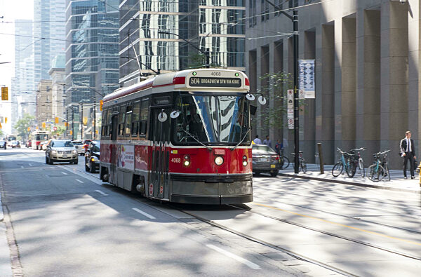 Eine rote Straßenbahn, die auf belebten Straßen in Toronto, Ontario, Kanada...