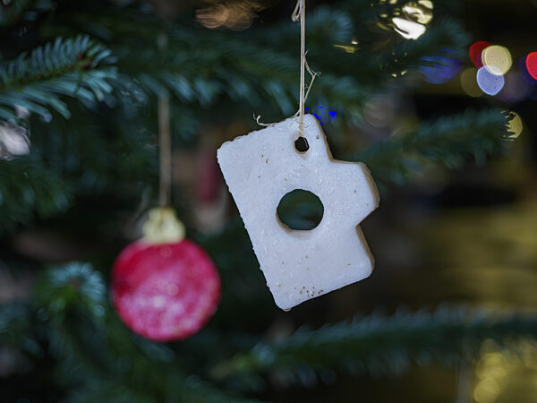 Nahaufnahme von Weihnachtsschmuck an einem Baum mit buntem Bokeh im...