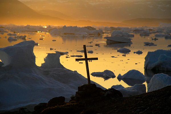Christliches Kreuz vor Eisbergen im orangen Abendlicht, Parnakajiit, Sermilik Fjord, Ost-Grönland, Arktis