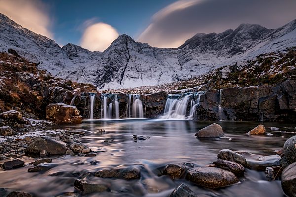 Kleiner Fluss mit Wasserfall in verschneiter Landschaft mit winterlichen Cullins Bergen im Hintergrund, Carbost, Portree, Isle of Skye, Schottland, Großbritannien, Europa