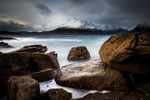 Große Felsen im Wasser der Nordsee mit verschneiten Cullin Bergen im Hintergrund, Elgol, Isle of Skye, Schottland, Großbritannien, Europa