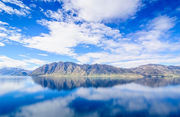 Wolkenhimmal mit Wasserspiegelung im See Hawea, Haast Pass, Südinsel, Neuseeland, Ozeanien