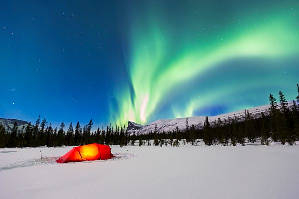 Nordlicht (Aurora borealis) über einem rot erleuchteten Zelt im Winter, Kungsleden, Provinz Lappland, Schweden, Europa