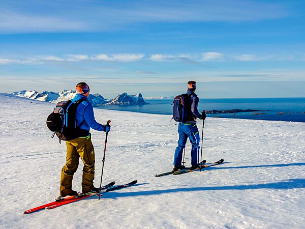 Zwei Skibergsteiger mit Blick aufs Meer, hinten der Teisten, Bergsjforden, Insel Senja, Troms, Norwegen, Europa