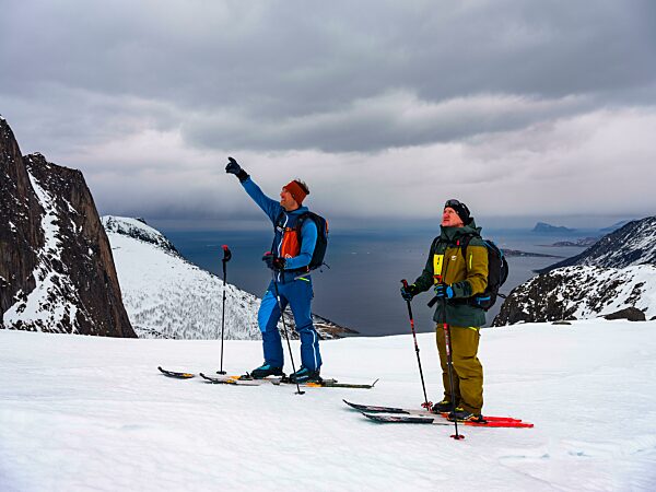Bergführer deutet seinem Gast den weiteren Weg, Skitour auf der Insel Senja, Troms, Norwegen, Europa
