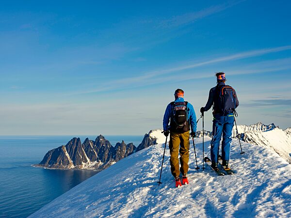 Zwei Skibergsteiger am Gipfel des Husafjellet mit Blick auf Devils Teeth, Okshornan, Insel Senja, Troms, Norwegen, Europa