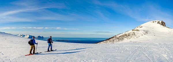 Panoramaaufnahme, Zwei Skibergsteiger am Husafjellet mit Blick aufs Meer, hinten der Teisten, Bergsjforden, Insel Senja, Troms, Norwegen, Europa