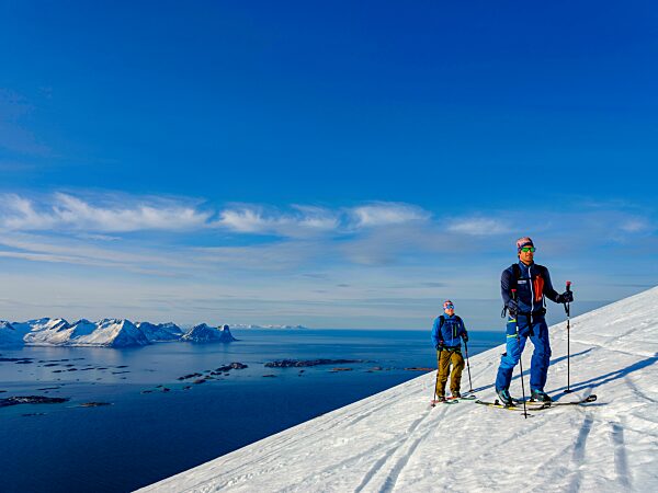 Zwei Skitourengeher im Aufstieg über dem Bergsfjord, Insel Senja, Troms, Norwegen, Europa