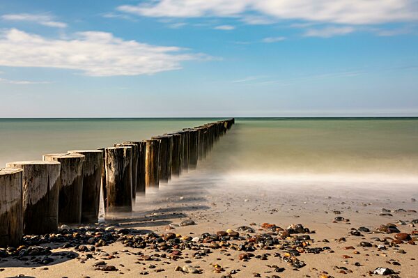 Langzeitbelichtung von Holzbuhnen in der Ostsee bei blauen Himmel im Frühling, Ostseebad Nienhagen, Mecklenburg-Vorpommern, Deutschland, Europa