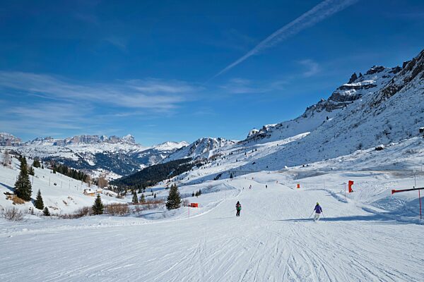 Blick auf eine Piste in einem Skigebiet mit Skifahrern in den Dolomiten in Italien. Canazei, Italien, Europa