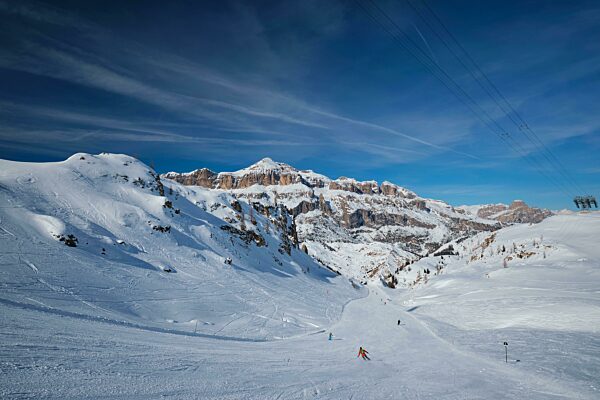 Blick auf die Piste eines Skigebiets mit Skifahrern in den Dolomiten in Italien mit einem Skilift. Skigebiet Arabba. Arabba, Italien, Europa