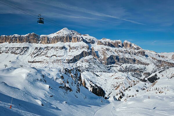 View of a ski resort piste with people skiing in Dolomites in Italy with cable car ski lift Ski area Arabba Arabba, Italy