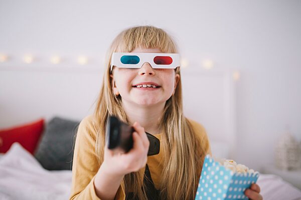 Fröhliches Mädchen vor dem Fernseher im Schlafzimmer