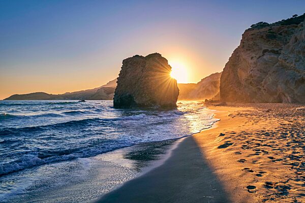 Bunte Sonnenuntergang über Fyriplaka Strand, Milos Insel, Kykladen, Griechenland. Schöner Himmel, einzigartige einsamen Felsen am Sandstrand, niedrige Sonne, Sonnenuntergang Dunst, felsigen Hügeln, Sonnenstrahlen, Meer Wellen Spray