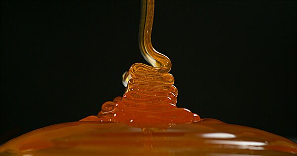 Honig fließt gegen schwarzen Hintergrund