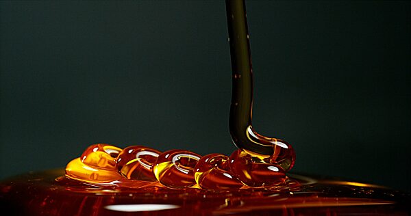 Honig fließt gegen schwarzen Hintergrund