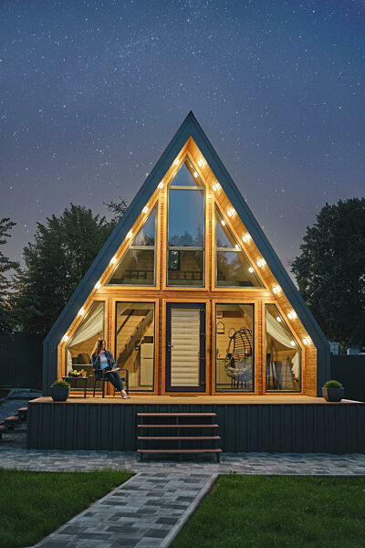 Eine dreieckige, von innen beleuchtete Blockhütte steht unter einem...