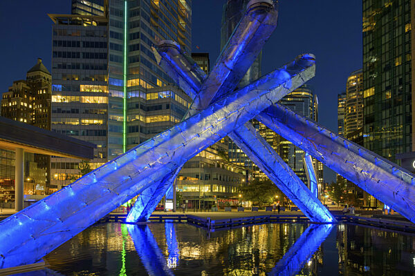 Moderne olympische Feuerinstallation bei Nacht mit blauer Beleuchtung und...
