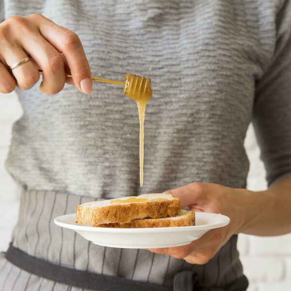 Vorderansicht Frau gießt Honig auf Brotscheibe