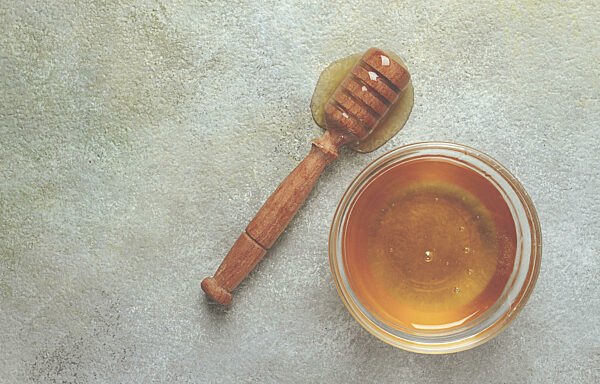 Holzlöffel mit Honig, auf dem Tisch, Spindel für Honig, Muskatblüte...