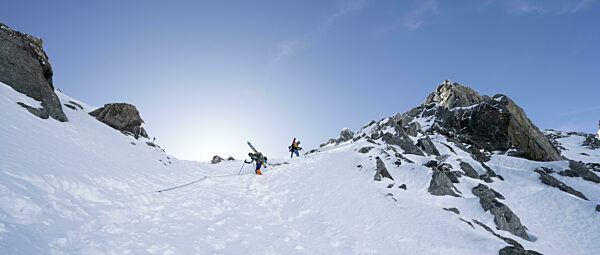 Bergsteiger mit Ski beim Abstieg durch ein steiles Schneefeld an der Porta...
