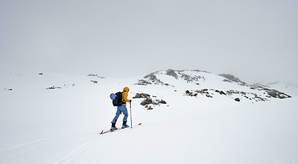 Skitourengeher in winterlicher Berglandschaft mit wolkenverhangenen...