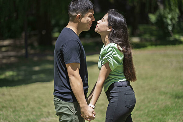 Ein lateinamerikanisches Paar hält sich die Hände und küsst sich in einem...