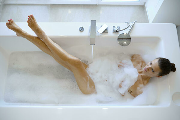 Eine schlanke Frau genießt ein entspannendes Schaumbad in einem modernen...