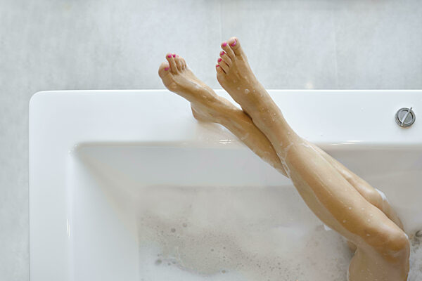 Ein Paar Füße mit leuchtend rosafarbenem Lack ruht elegant über dem Rand...