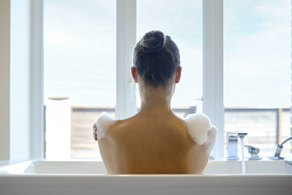 Eine unerkennbare Frau genießt ein beruhigendes Bad in einer modernen Wanne...