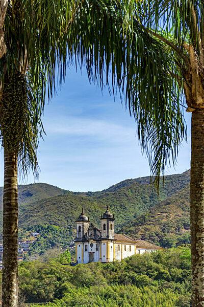 Historische Barockkirche durch die Bäume mit den Bergen der Stadt Ouro Preto...