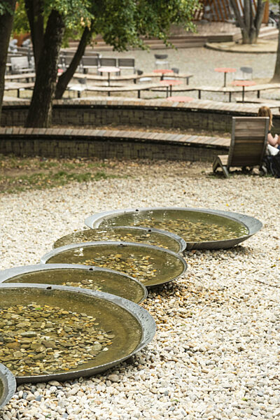 Kleiner Park mit Sitzmöglichkeiten, einem Spielplatz und einem Brunnen am...