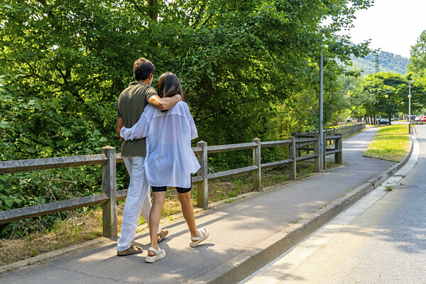 Romantisches Paar, das auf einem gepflasterten Weg in einem Park spazieren...