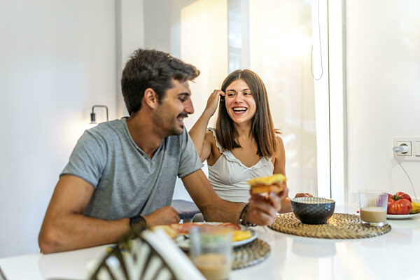 Junges Paar beim Frühstück zu Hause, lachend und fröhliche Momente...