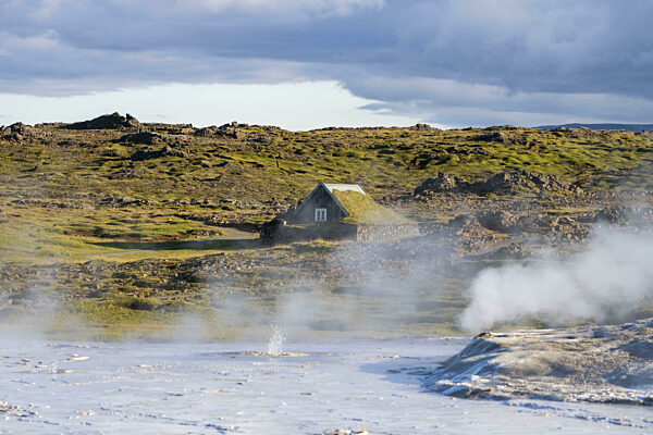 Dampfende Quellen und traditionelles Haus beim Geothermalgebiet Hveravellir...