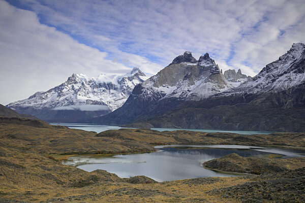 Schneebedeckte Gipfel und ruhige Seen erstrecken sich unter einem weiten...