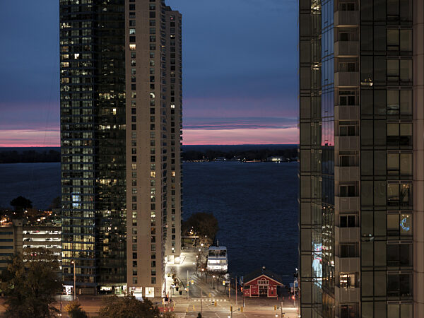 Blick auf den Sonnenaufgang mit Wolkenkratzern an einem See und einem...