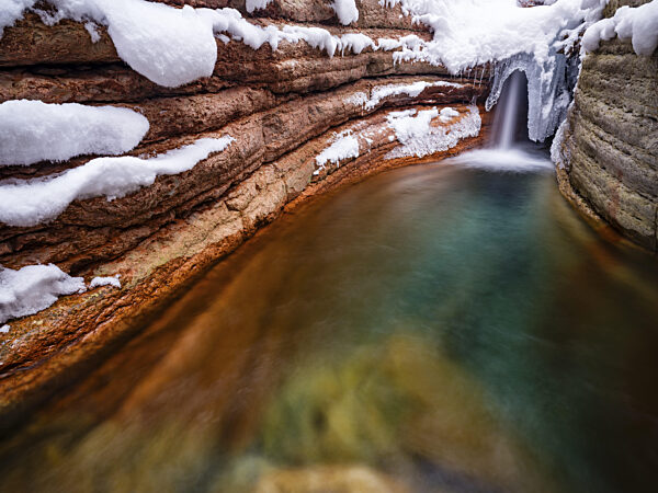 Taugl oder Tauglbach fließt durch die verschneite und vereiste rote Klamm...