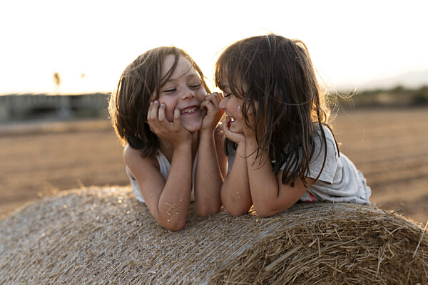 Zwei kleine Kinder teilen einen freudigen Moment auf einem Heuballen auf...